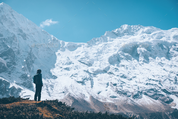 Woman on the mountain trail and looking on snow covered rocks - Stock Photo - Images
