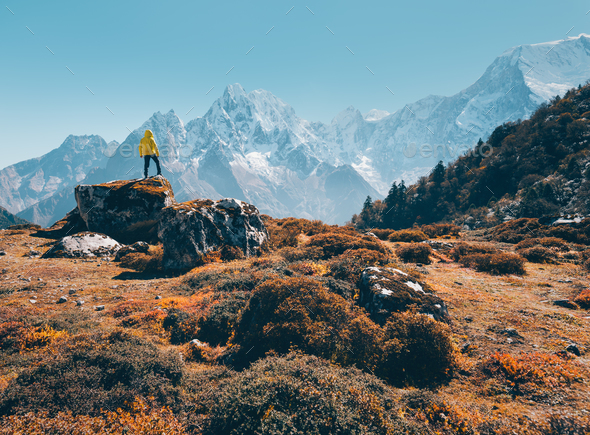 Standing man on the stone against snowy mountains - Stock Photo - Images
