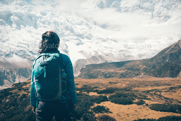 Woman with backpack looking on snow covered mountains - Stock Photo - Images