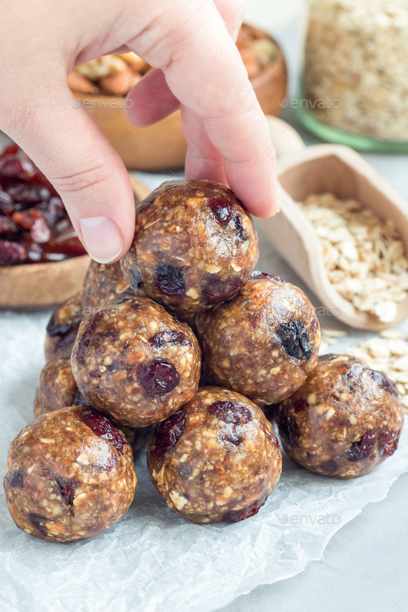 Healthy homemade energy balls with cranberries, nuts, dates and rolled oats on parchment, vertical Stock Photo by iuliia_n