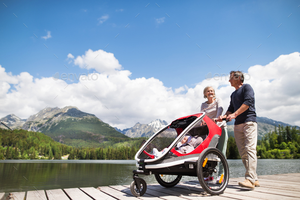 Senior couple with grandchildren in jogging stroller. Stock Photo by halfpoint