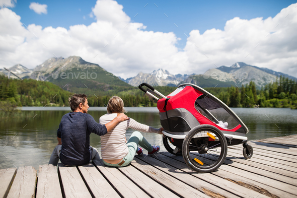 Senior couple with jogging stroller, summer day. Stock Photo by halfpoint