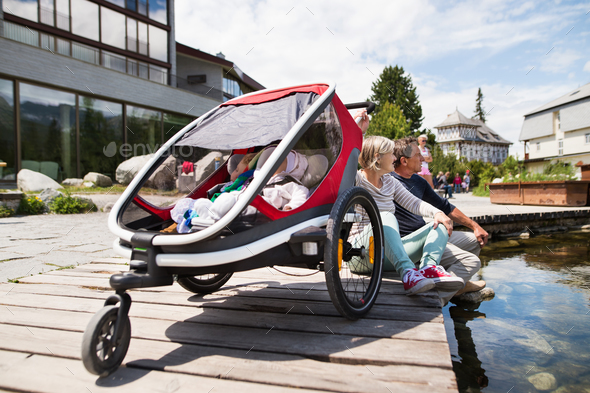 Senior couple with grandchildren in jogging stroller. Stock Photo by halfpoint