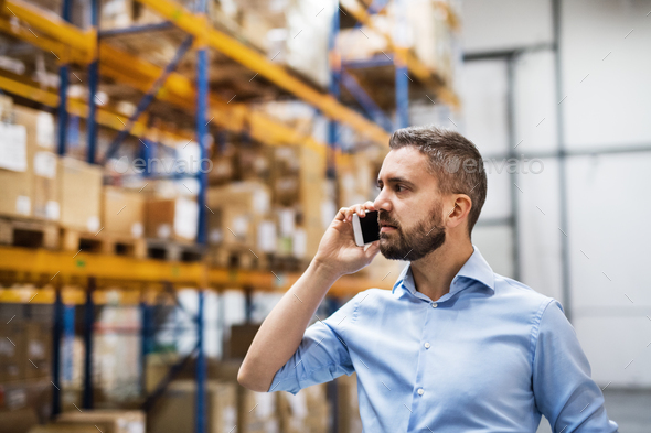 Warehouse worker or supervisor with a smartphone. Stock Photo by halfpoint