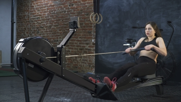 Fitness Woman Doing Rowing Machine Workout in Cross Fit Gym