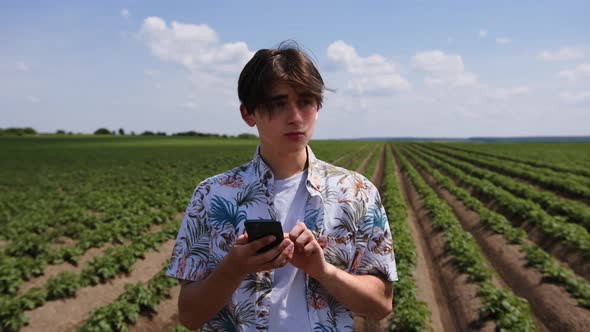 Close Up Young Man Stand in Green Field Use Mobile Phone Agricultural Industry Job Nutrition Organic