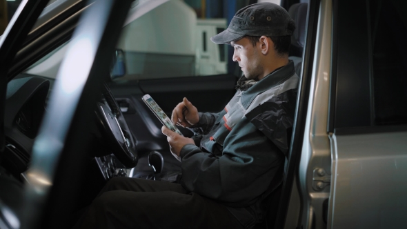 The Repairman, Who Is Dressed in a Working Uniform, Is in the Vehicle and Checks the Gearbox alt