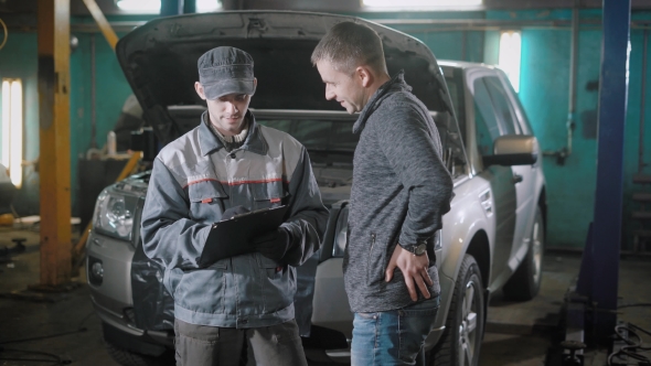 a Man with a Broken Car Turned To a Service for Repairing a Vehicle in a Tire Service alt