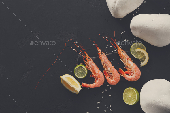 Shrimps with lemon and stones on black background - Stock Photo - Images