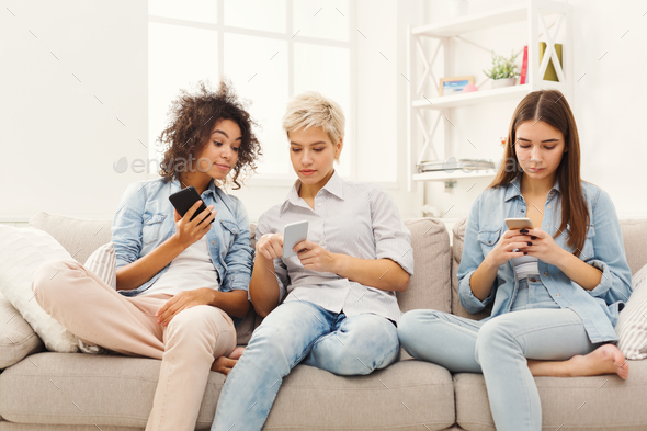 Three female friends using smartphones at home - Stock Photo - Images