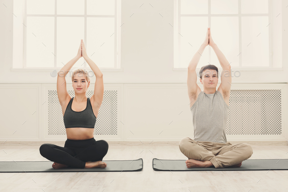Young couple practicing yoga sitting in padmasana Stock Photo by Milkosx