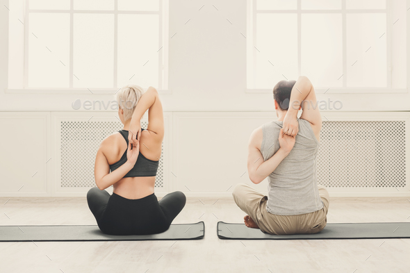 Young couple in yoga class, back stretching Stock Photo by Milkosx
