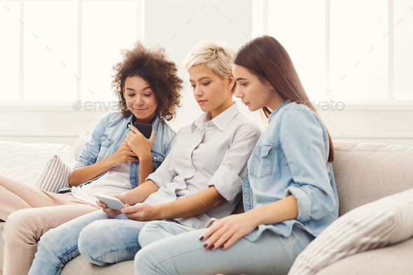 Three female friends using smartphones at home - Stock Photo - Images