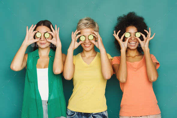Three beautiful girls covering eyes with cucumber pieces Stock Photo by Milkosx