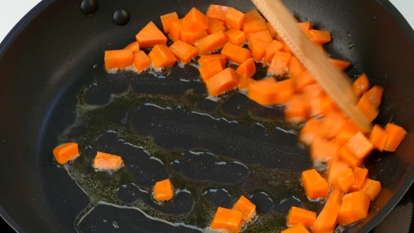 To Stir Slices of Fried Carrots in Oil on a Frying Pan