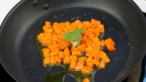 Fry Pieces of Carrots in Oil in a Frying Pan with Broccoli