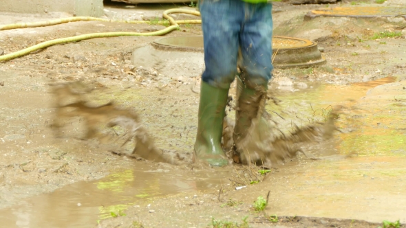 Boy with an Umbrella Jumping in a Puddle
