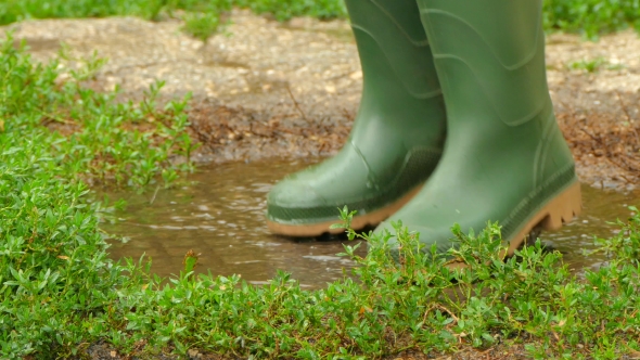 Feet in Rubber Boots Fun To Jump Across the Puddle