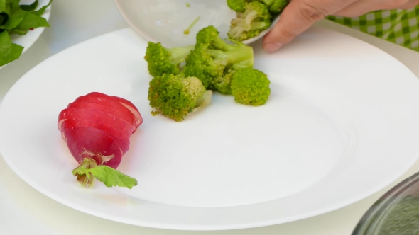 Cook Lays Chicken with Vegetables on a Plate