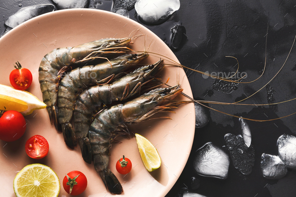 Raw shrimps with lemon on black background - Stock Photo - Images