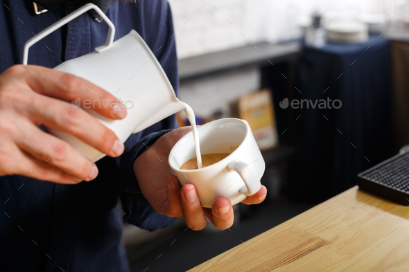 Closeup of barmen pouring milk to cappuccino cup - Stock Photo - Images