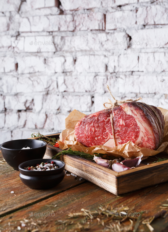 Raw aged prime black angus beef in craft papper on rustic wood - Stock Photo - Images