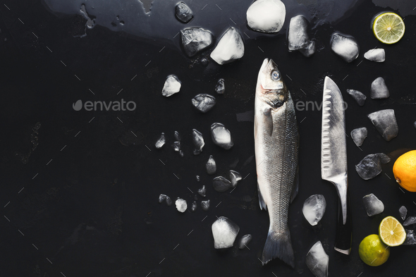 Fresh sea bass with ice at black background - Stock Photo - Images
