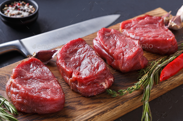 Filet mignon steaks and spices on wood at black background - Stock Photo - Images