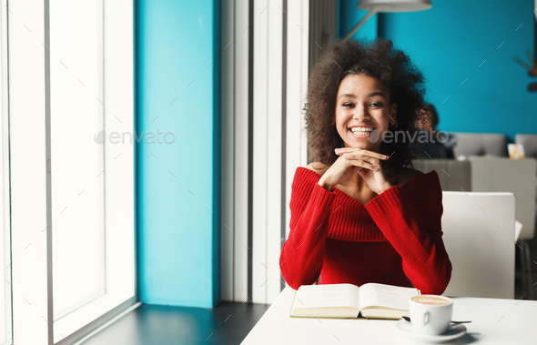 Happy black girl at cafe reading a book - Stock Photo - Images