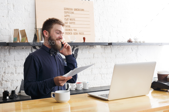Pensive barman working on laptop at bar counter - Stock Photo - Images