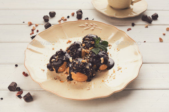 French profitroles with chocolate icing and mint leaves - Stock Photo - Images