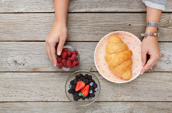 Female hands serving breakfast table with croissant and berries - Stock Photo - Images