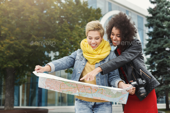 Two girl friends outdoors with paper city map - Stock Photo - Images