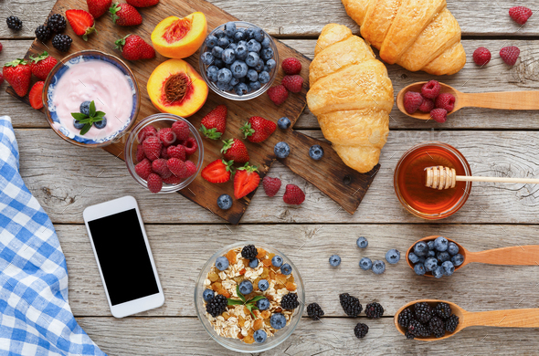 Morning meals and smartphone on rustic wooden table - Stock Photo - Images