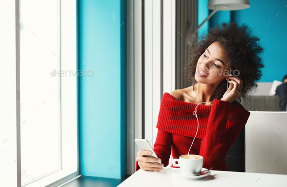 Happy black girl at cafe listening to music - Stock Photo - Images