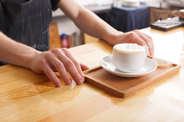 Barman serving coffee cup on wooden bar counter - Stock Photo - Images