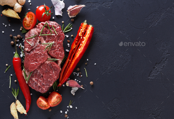 Rib eye steak, spices and vegetables at black background - Stock Photo - Images