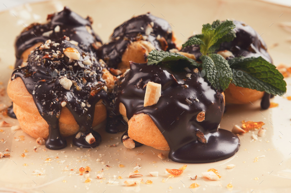 French profitroles with chocolate icing and mint leaves - Stock Photo - Images