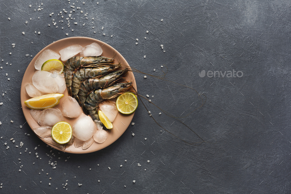 Raw shrimps with lemon on black background - Stock Photo - Images