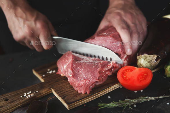 Chef cutting filet mignon on wooden board at restaurant kitchen - Stock Photo - Images
