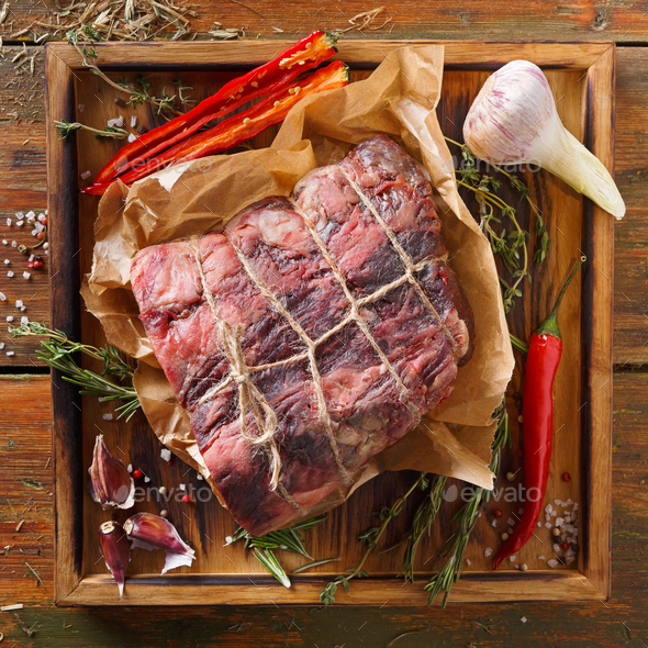 Raw aged prime black angus beef in craft papper on rustic wood - Stock Photo - Images