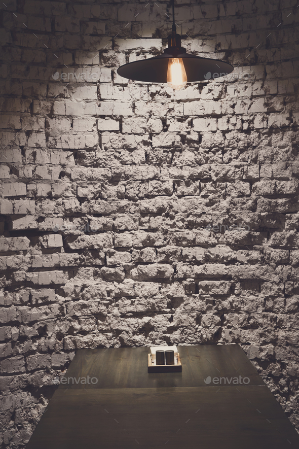 Brick grunge wall and ceiling lamp above table - Stock Photo - Images