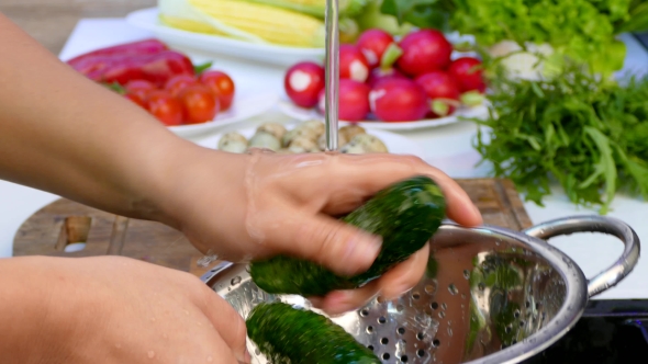 Hands Wash the Cucumbers in a Sieve.