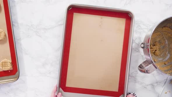 Flat lay. Step by step. Scooping peanut butter cookies dough with dough scooper into the baking shee alt