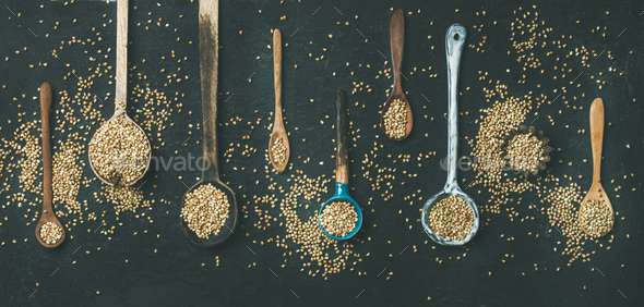 Various kitchen spoons full of green buckwheat grains, top view - Stock Photo - Images