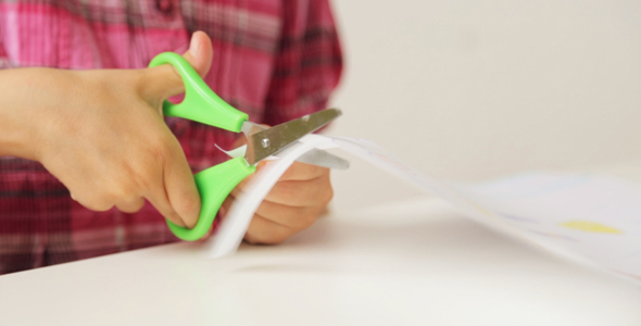 Child's Hands Cutting Paper with Scissors