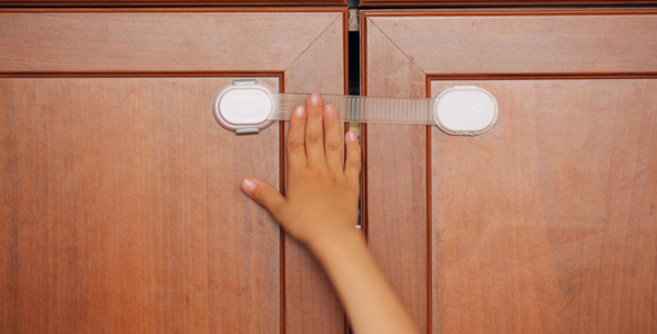 Furniture Safety Lock and Child's Hand on It