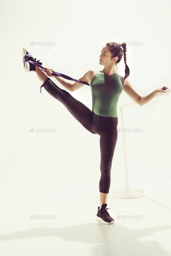 The brunette athletic woman exercising with rubber tape