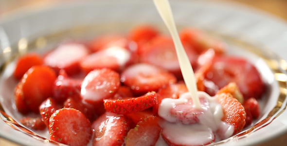 Pouring Fresh Milk Into Bowl Full of Strawberry