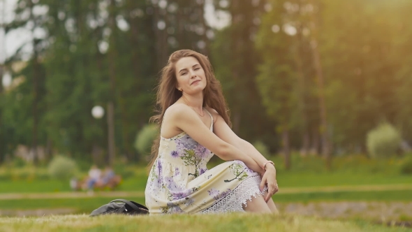 A Young Beautiful Girl with Long Hair in a Summer Dress Is Sitting on a ...